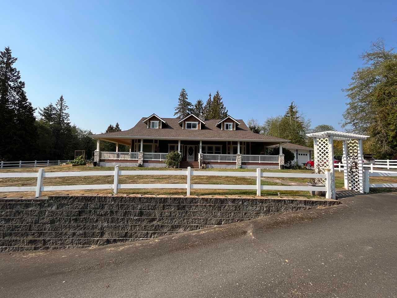 A large house with a white fence around it taken by Riverside Roofing