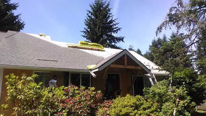A man is working on the roof of a house taken by Riverside Roofing