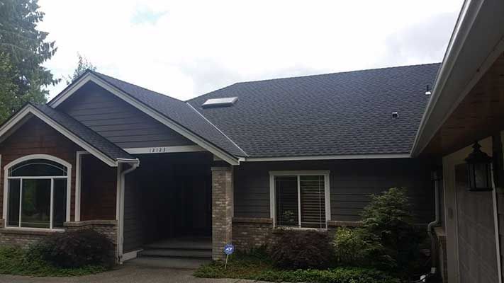 A large house with a black roof and a lot of windows taken by Riverside Roofing