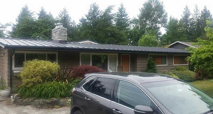 A black car is parked in front of a house taken by Riverside Roofing