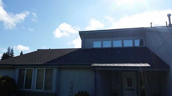 A house with a roof and a lot of windows on a sunny day taken by Riverside Roofing