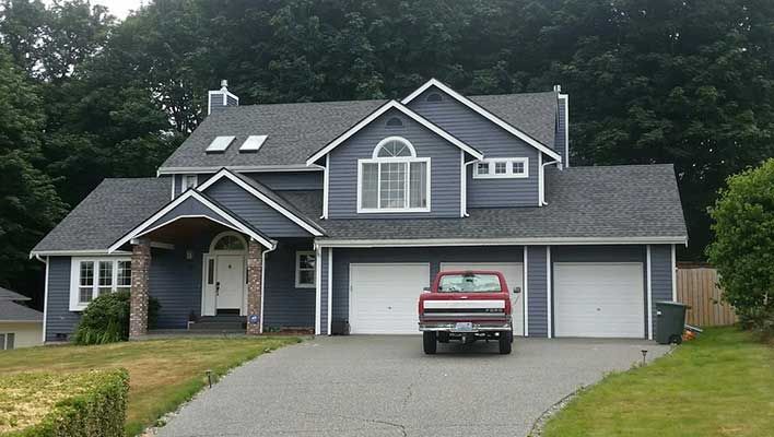 A red truck is parked in front of a large house taken by Riverside Roofing