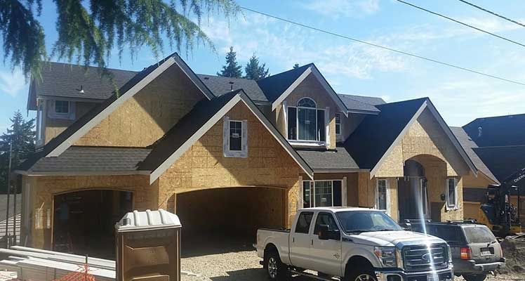 A white truck is parked in front of a house under construction taken by Riverside Roofing