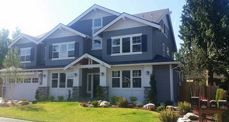 A large house with a lot of windows is sitting on top of a lush green lawn taken by Riverside Roofing