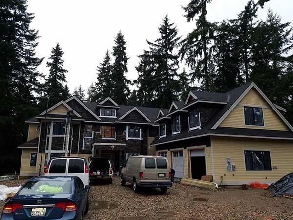 A large house under construction with cars parked in front of it taken by Riverside Roofing