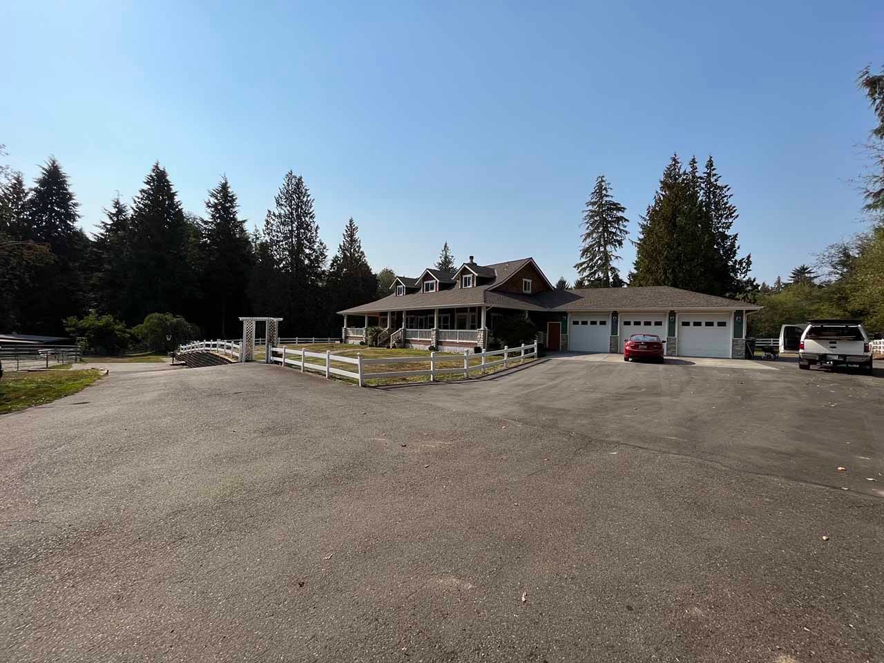 A house with two garages and a fence in front of it taken by Riverside Roofing