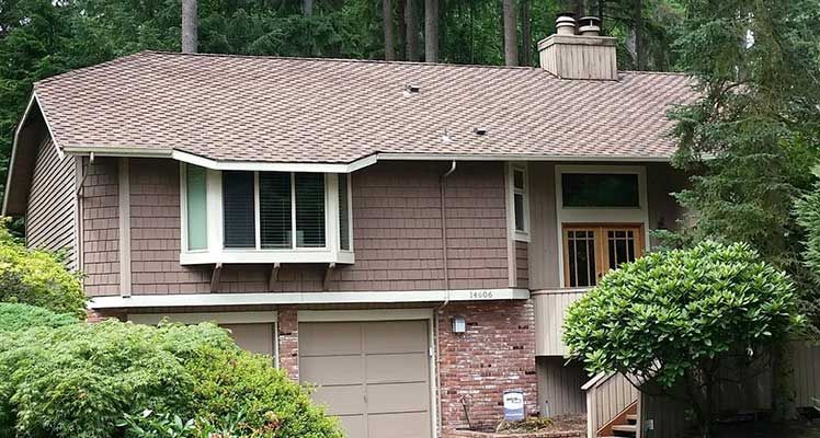 A house with a brown roof and a large window taken by Riverside Roofing