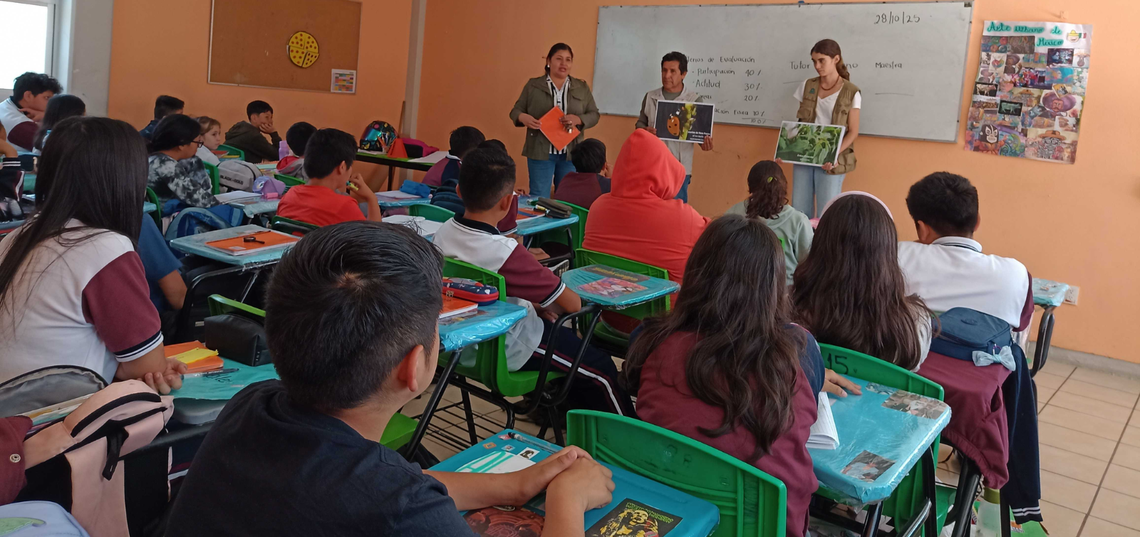 Clase en el aula con los alumnos sentados en sus pupitres frente a un profesor situado al frente de la sala.