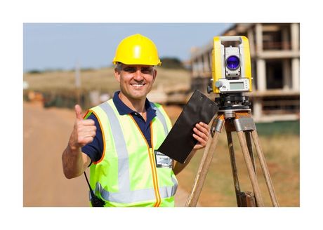 surveyor giving the thumbs up beside his tripod
