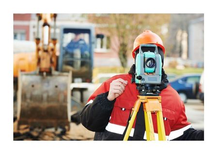 surveyor looking through viewer on tripod with excavator behind him