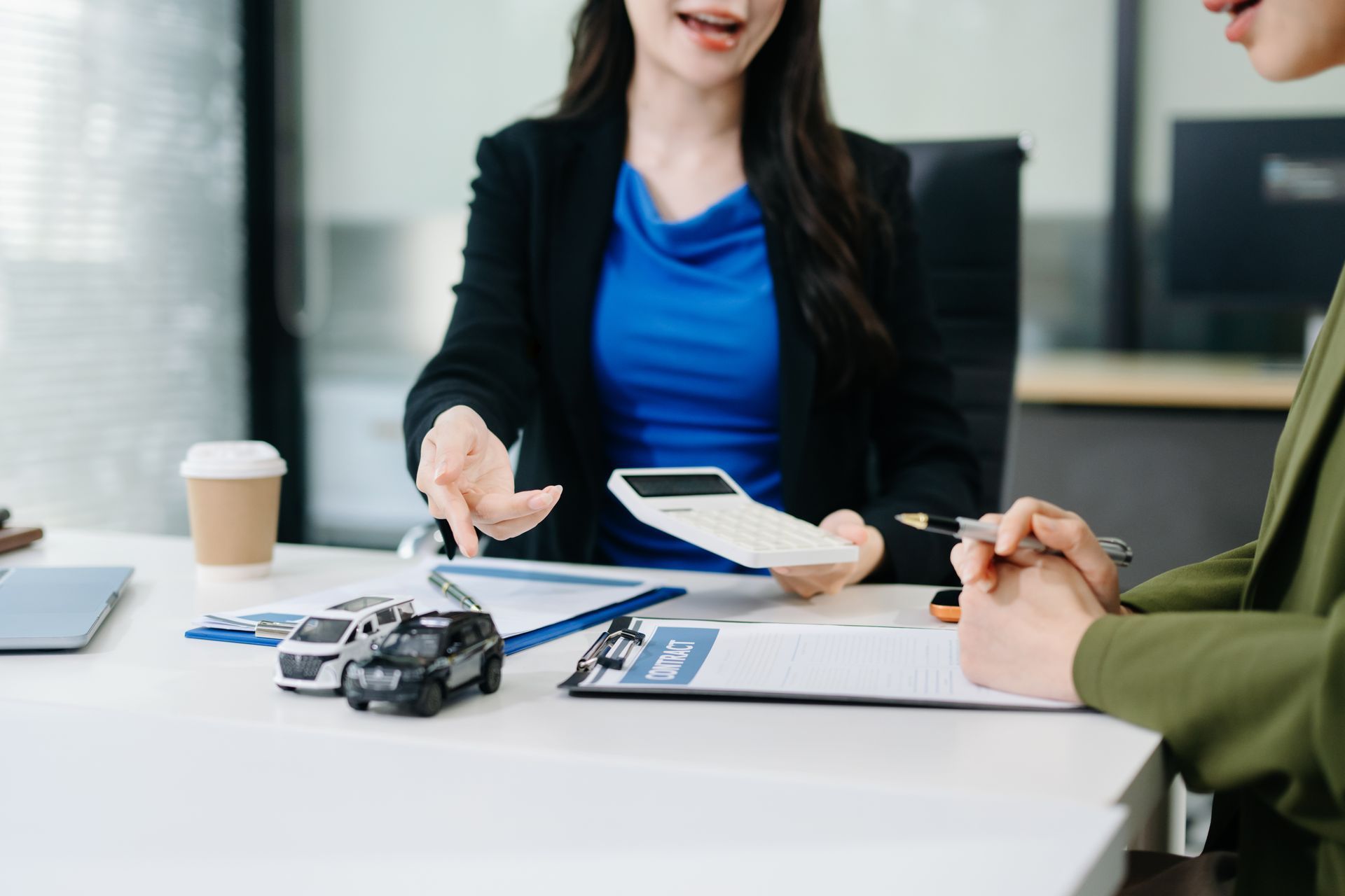 An agent and a business owner are discussing commercial auto insurance in an office. An agent and a business owner are discussing commercial auto insurance in an office.