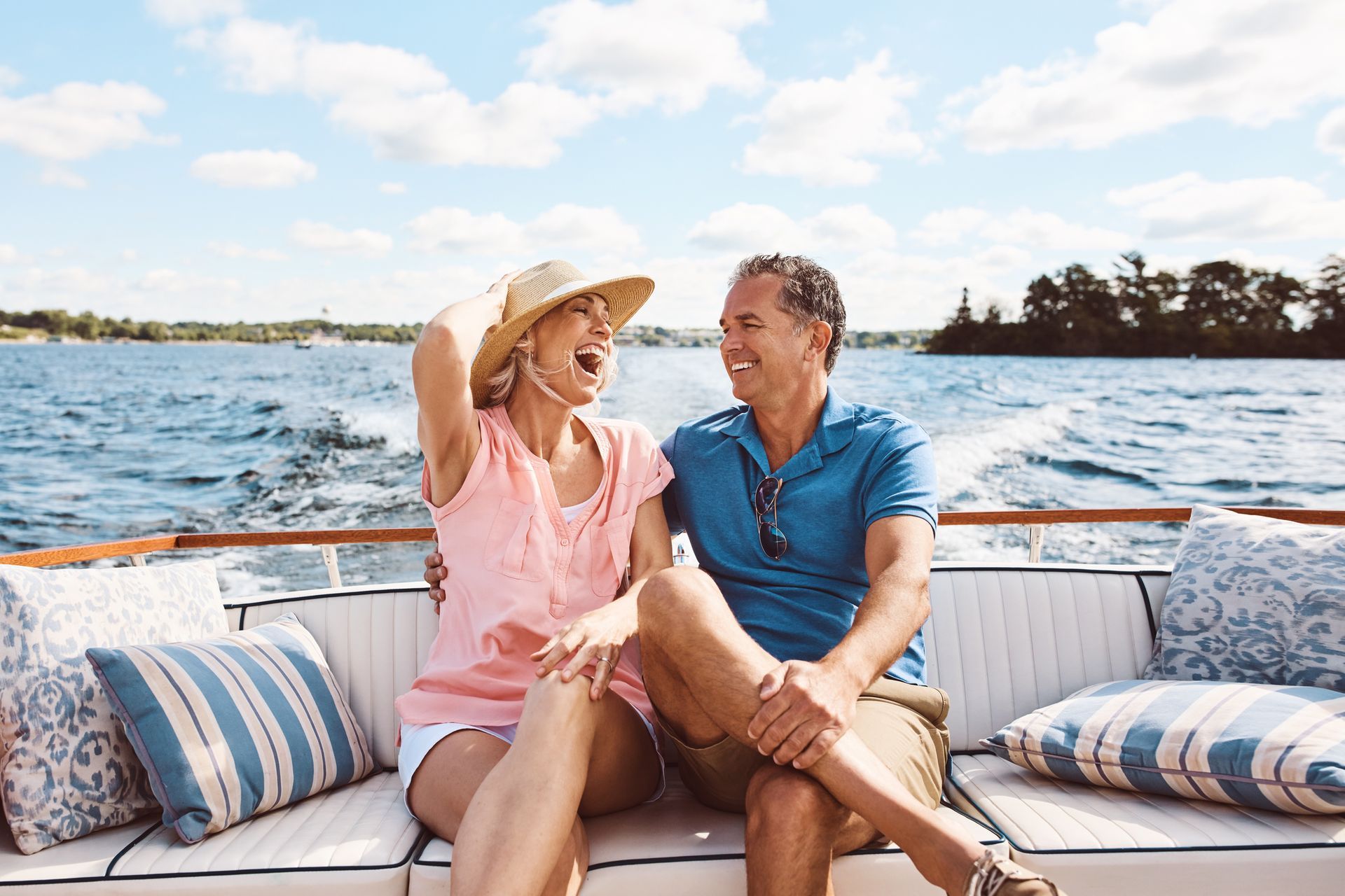 A smiling mature couple enjoying a relaxing boat ride, showcasing reliable boat insurance.