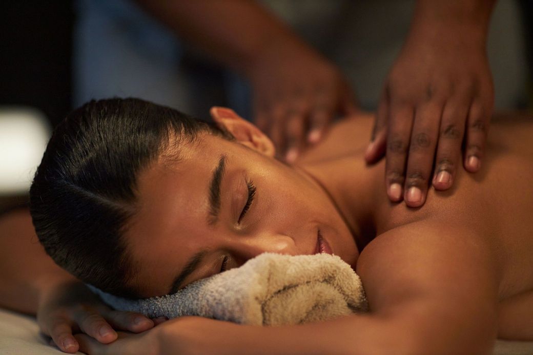 A person receives a relaxing facial massage in a spa, with a therapist’s hands resting on their forehead.