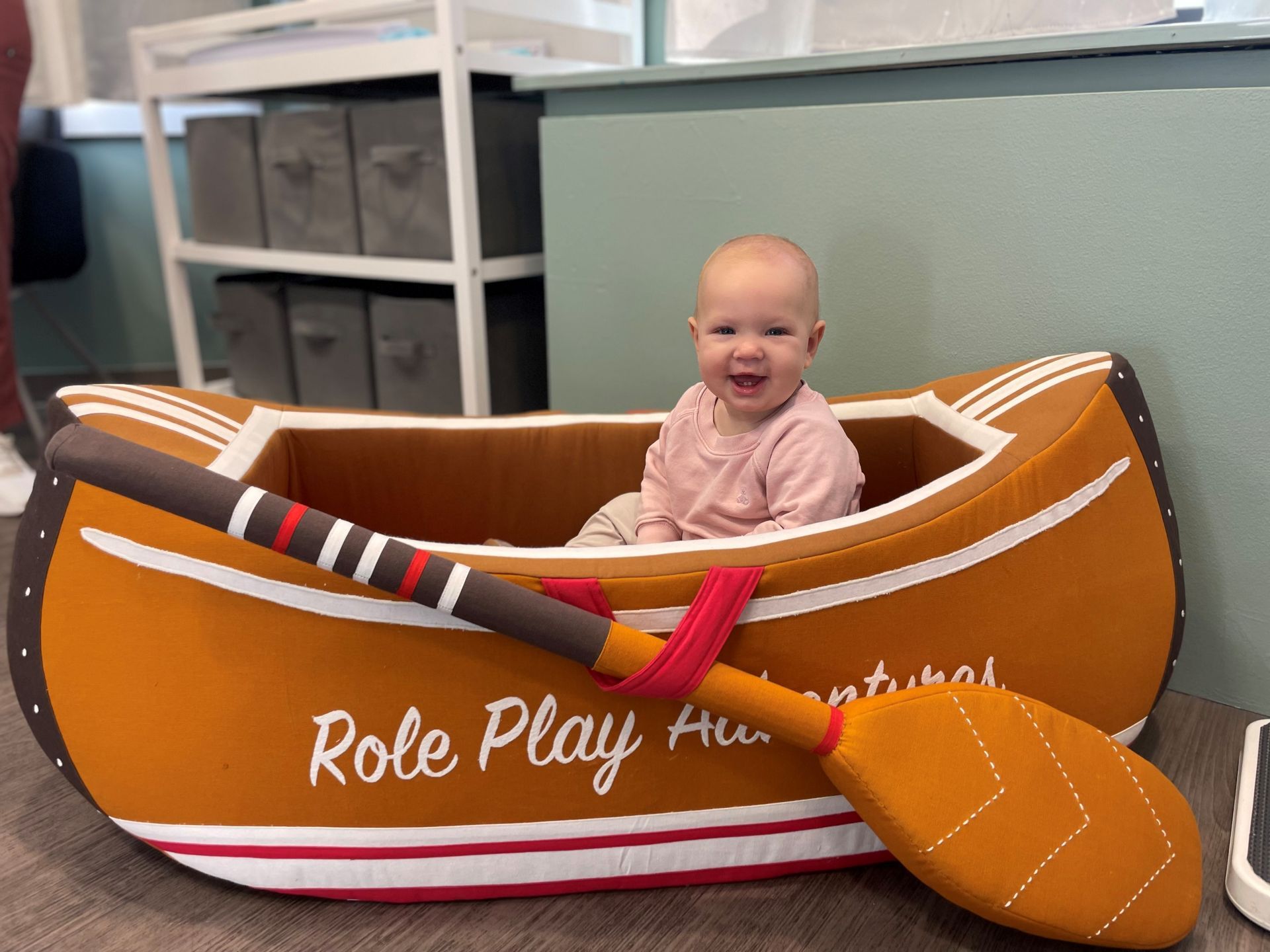 A baby is sitting in a canoe with a paddle.