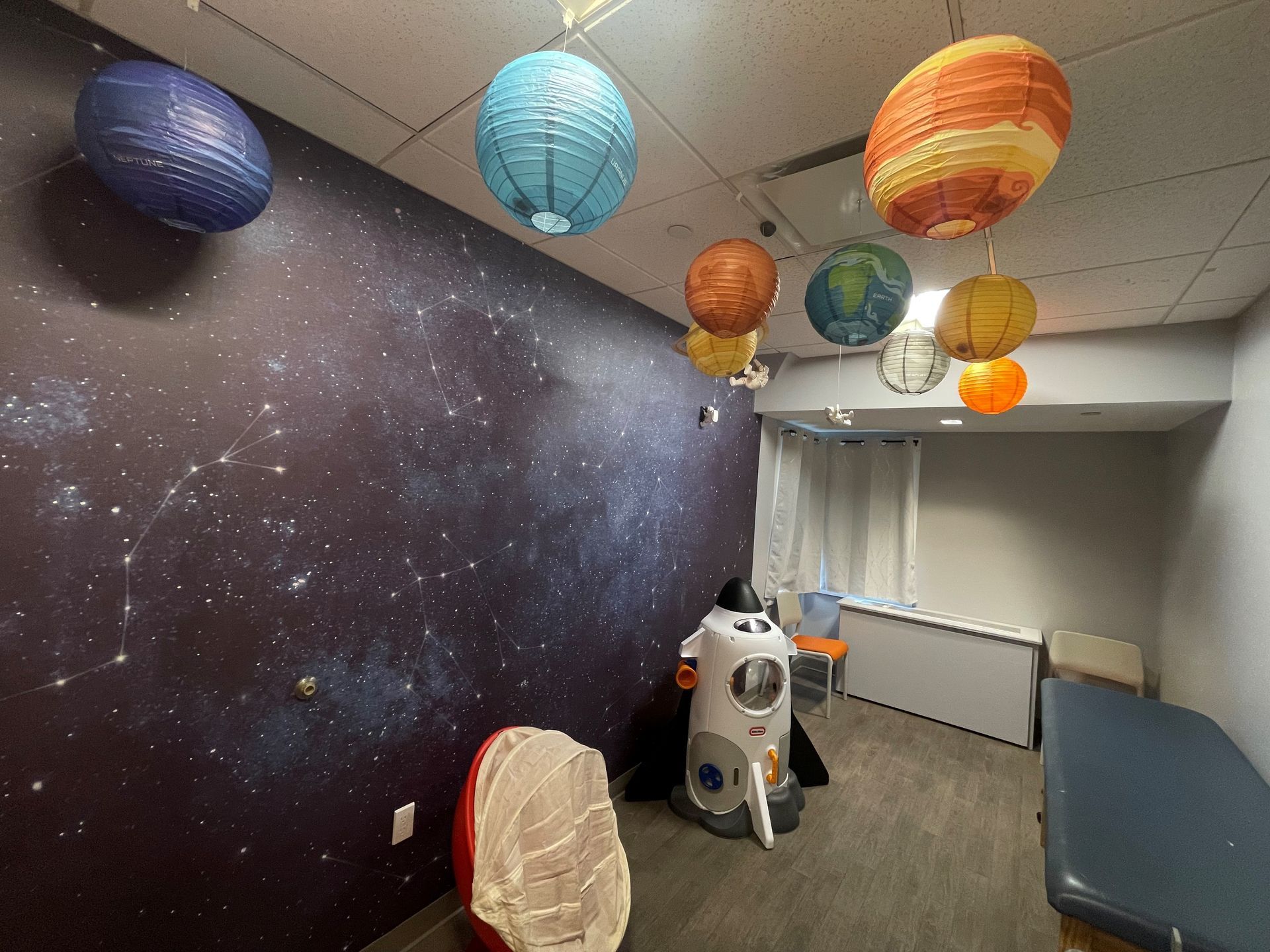 A room with a rocket and paper lanterns hanging from the ceiling.