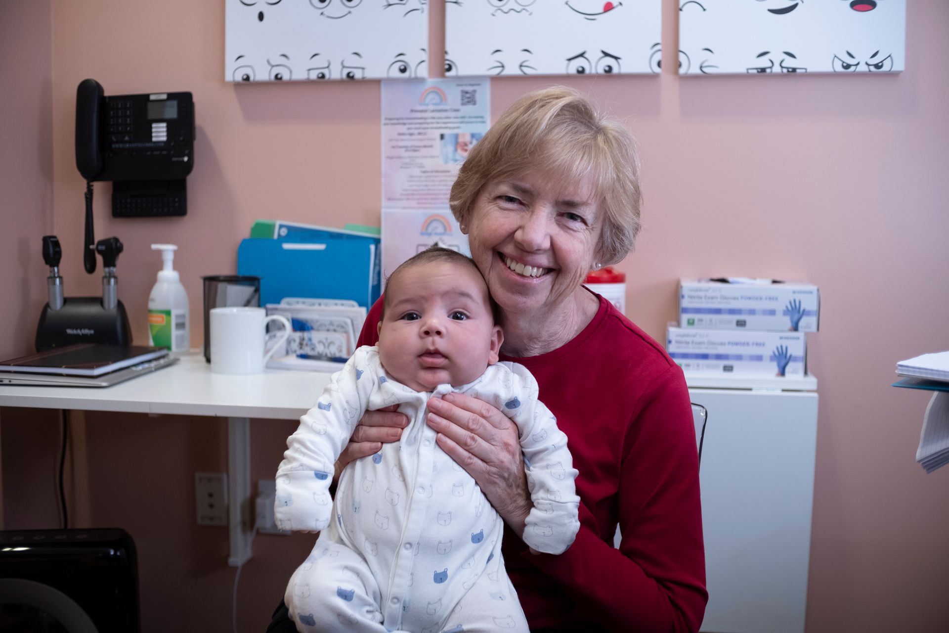 A woman is holding a baby in her arms in a doctor 's office.