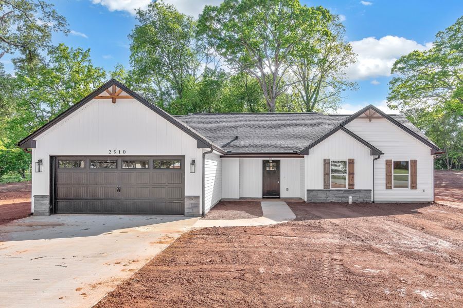 A white house with a black garage door is for sale.