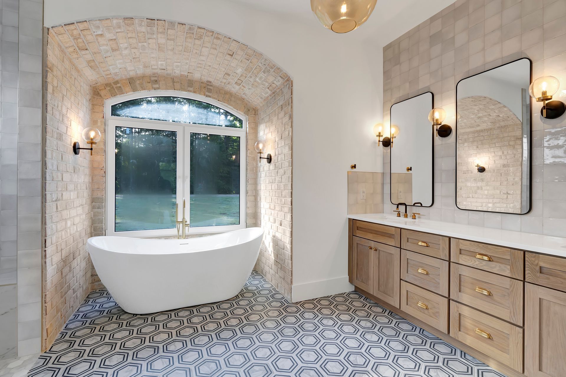 A bathroom with a tub , sinks , mirrors and a window.