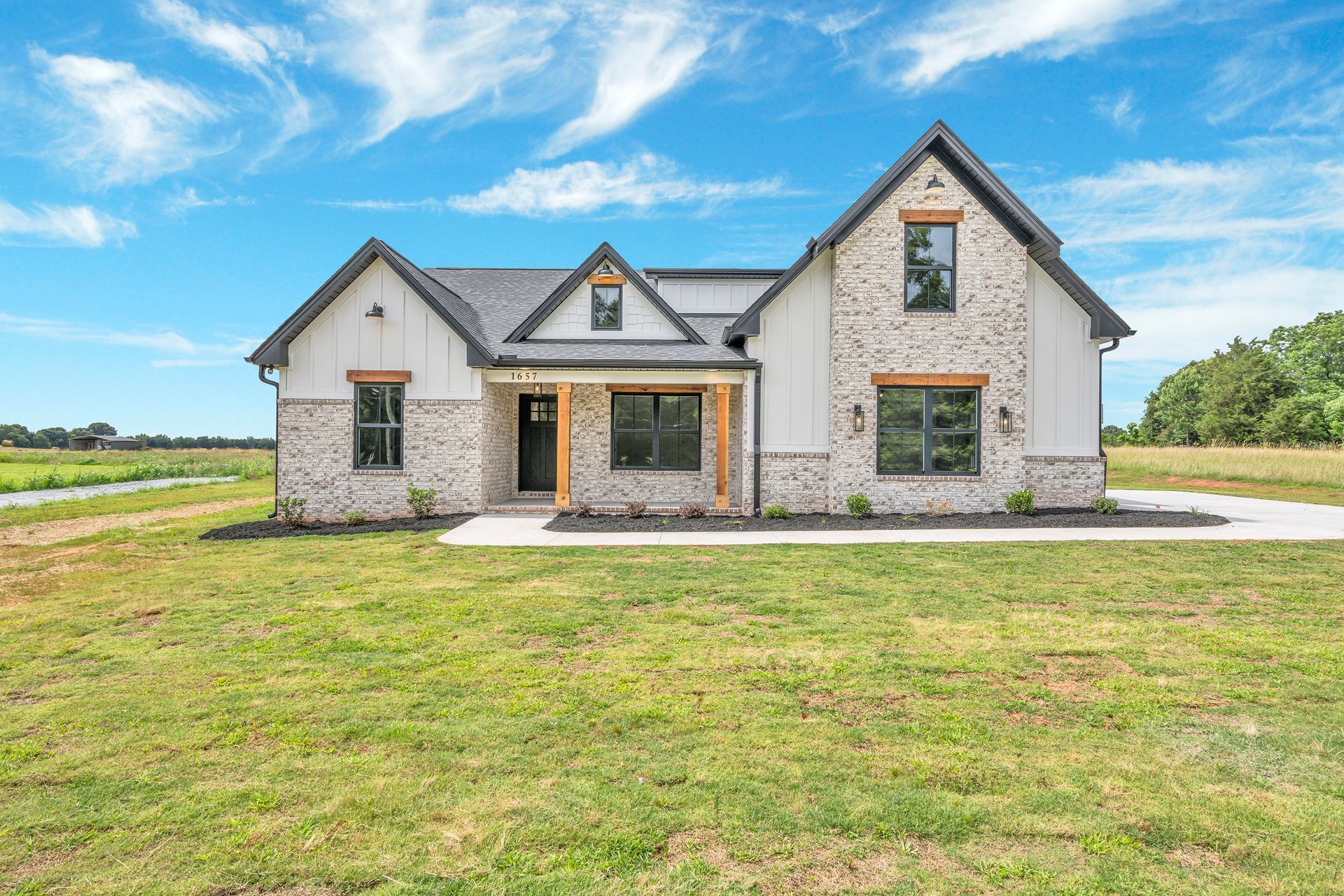 A large house with a lot of windows is sitting on top of a lush green field.