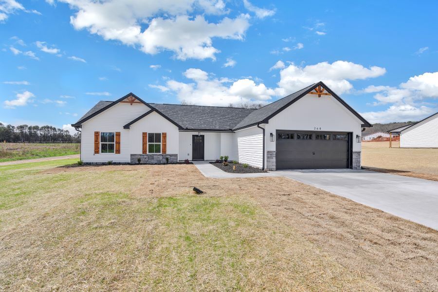 A white house with a black garage door is for sale.