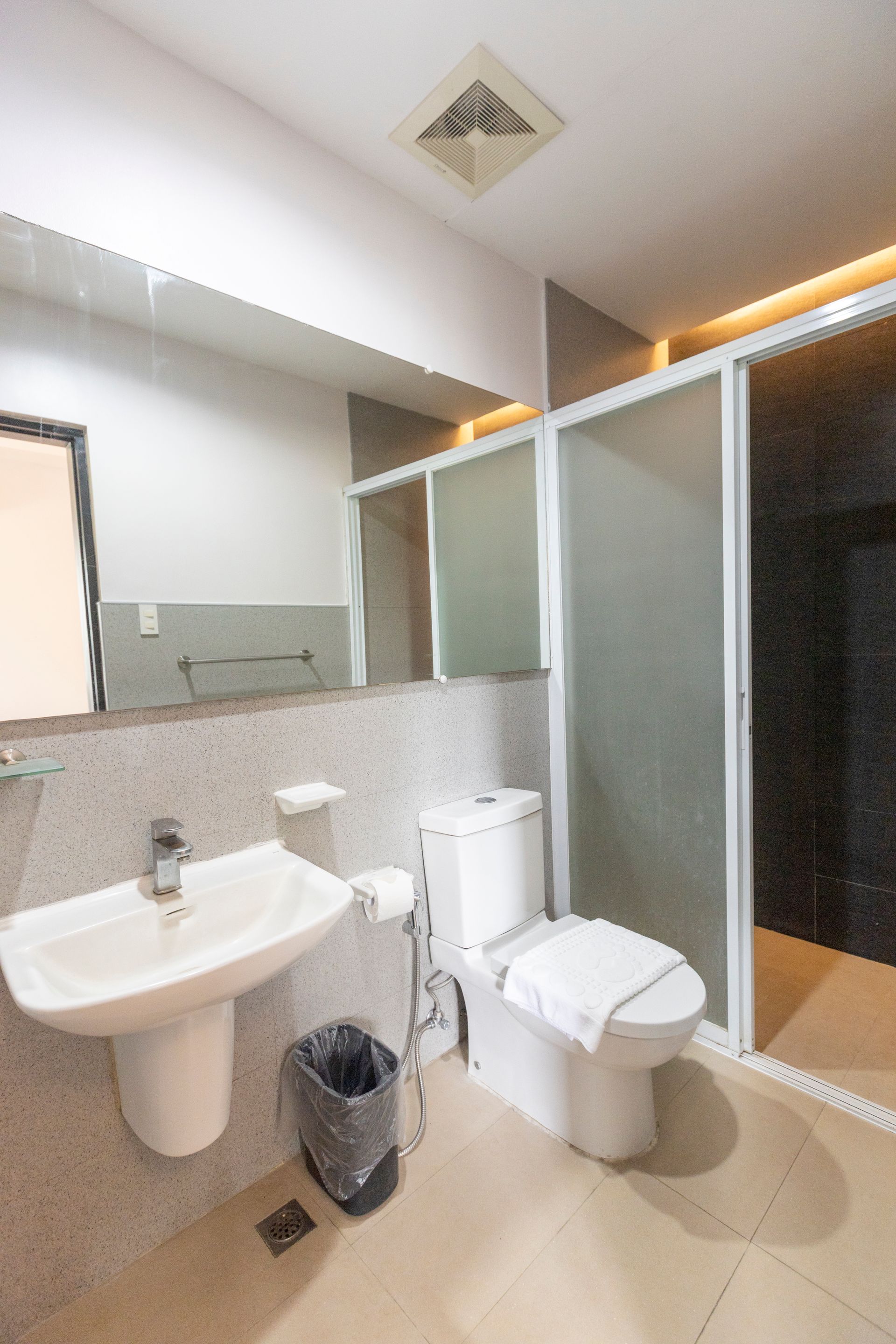 Bathroom with a sink, toilet, glass shower, and mirror. Gray and white color scheme.