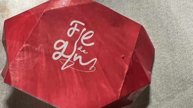 un oggetto origami rosso è seduto su una superficie bianca.