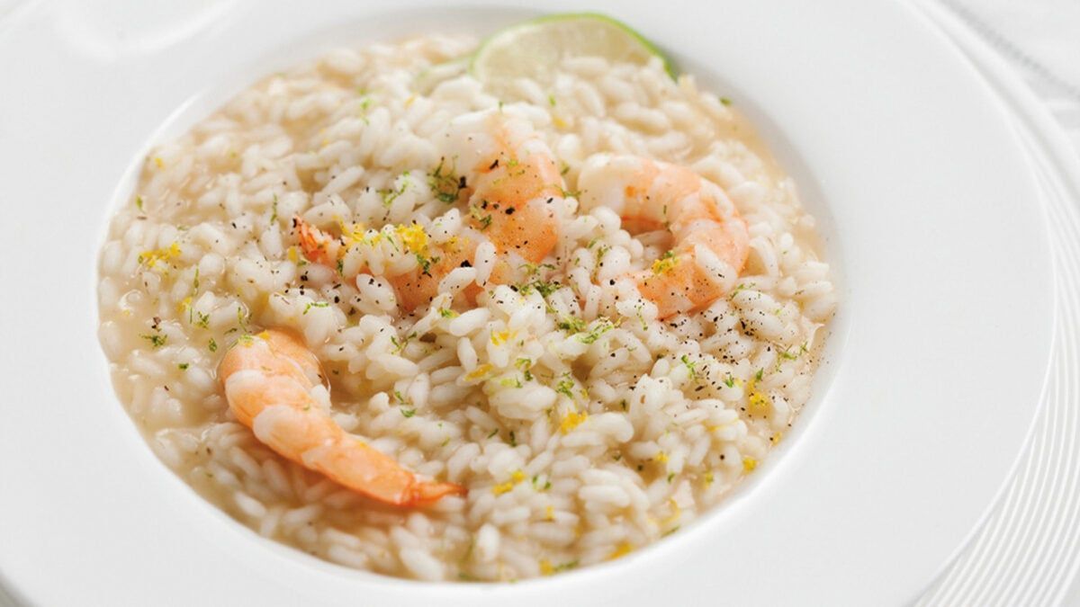 A white bowl filled with rice and shrimp on a table.