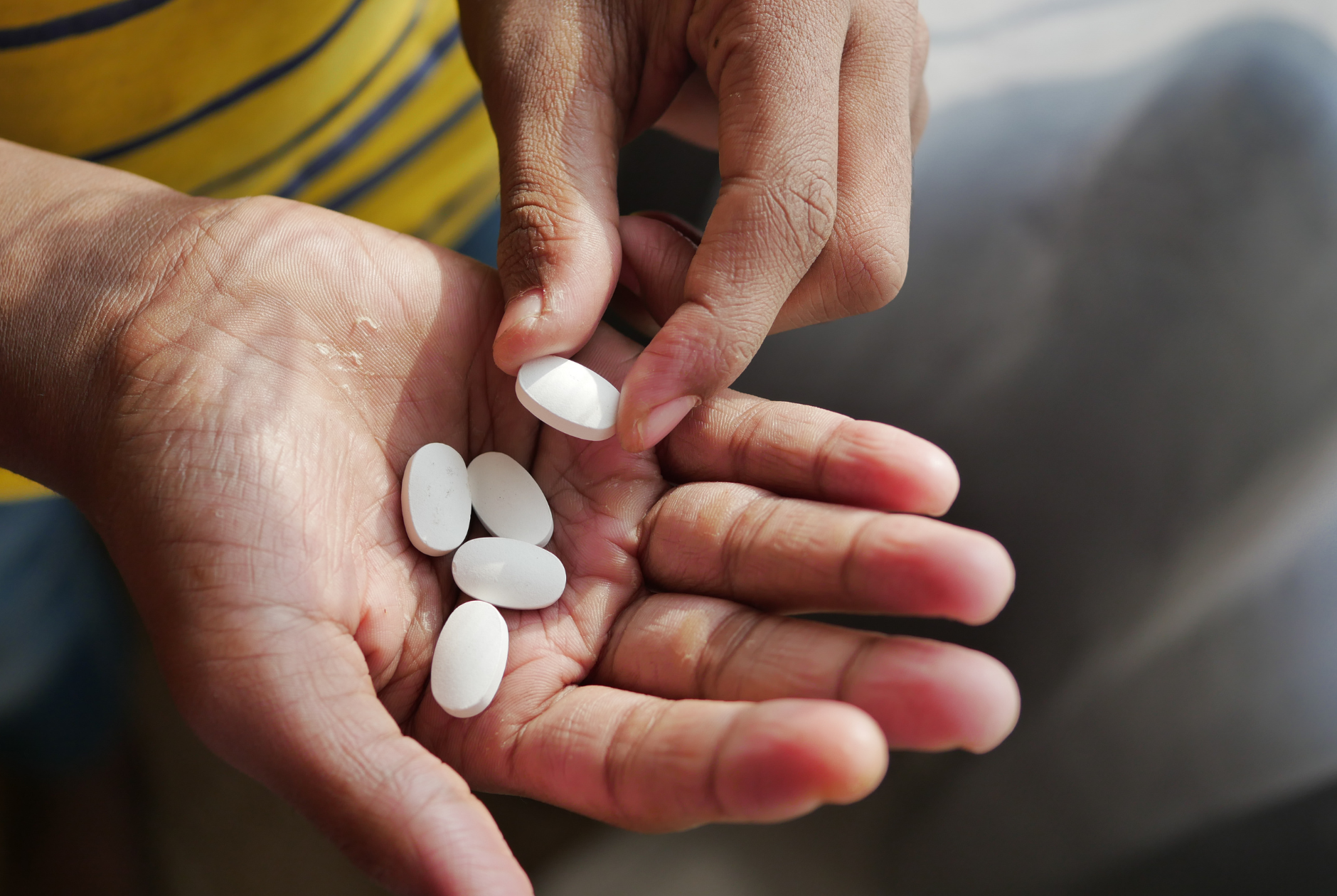A person is taking a pill out of their hand