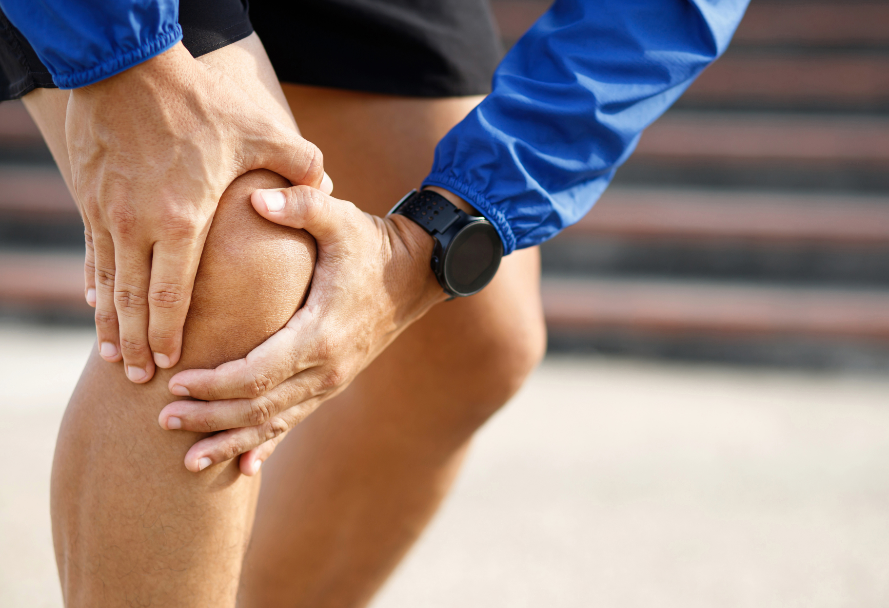 A man is holding his knee in pain.