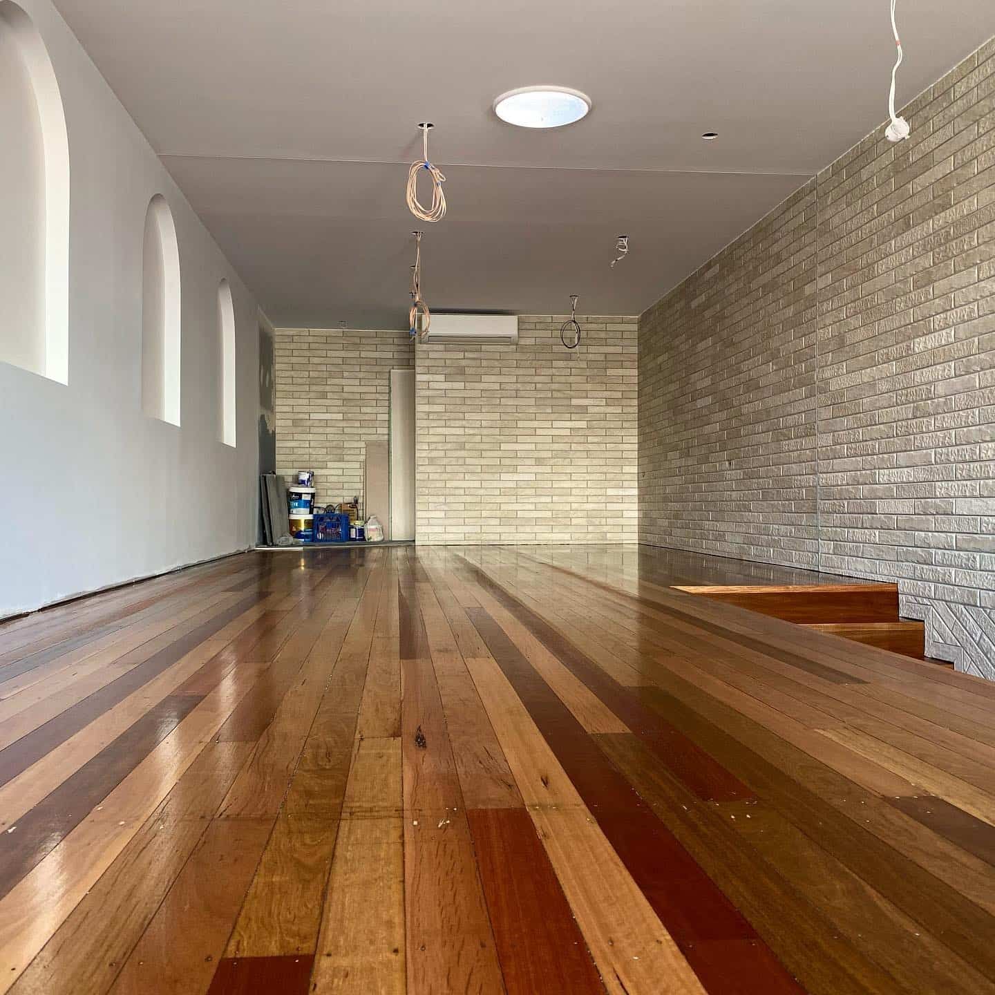 An Empty Room With a Wooden Floor and Brick Walls — JIC Projects Pty Ltd in Runaway Bay, QLD