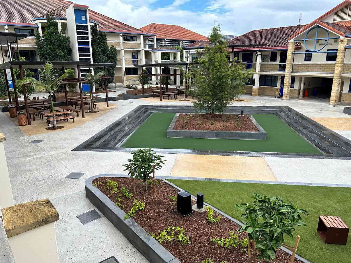 A Large Courtyard With a Fountain in the Middle of It Surrounded by Buildings — JIC Projects Pty Ltd in Runaway Bay, QLD