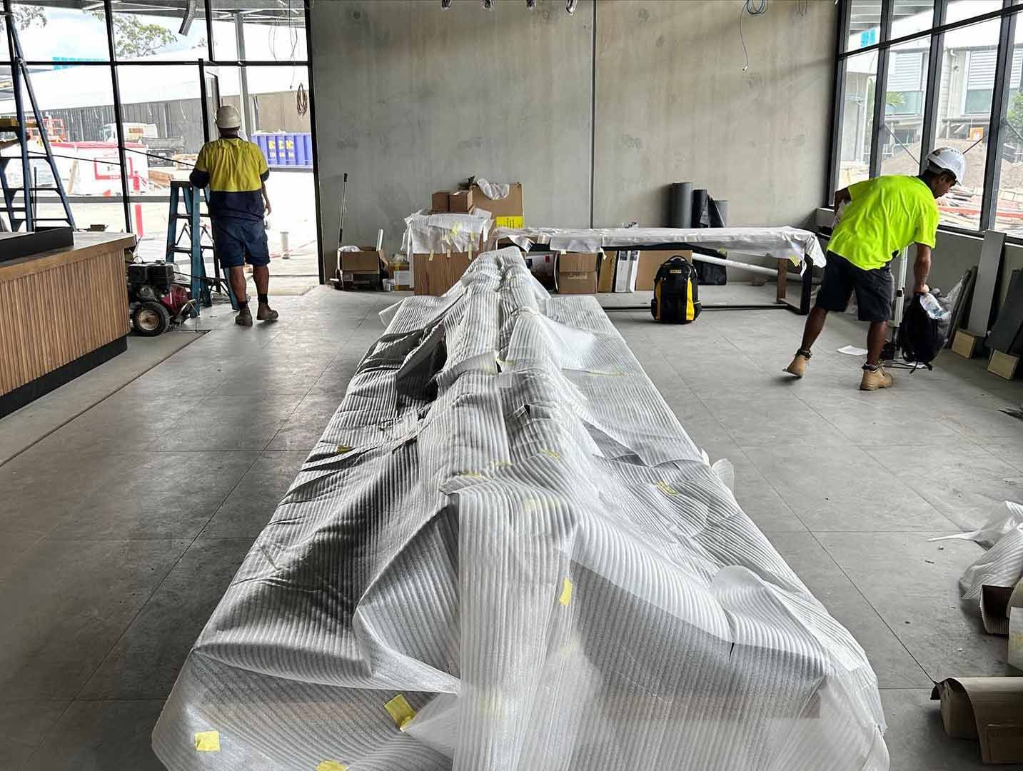 A Man is Standing Next to a Table Wrapped in Plastic — JIC Projects Pty Ltd in Runaway Bay, QLD