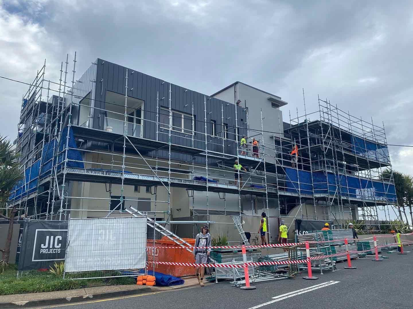 A Large Building is Being Built With Scaffolding Around It — JIC Projects Pty Ltd in Runaway Bay, QLD