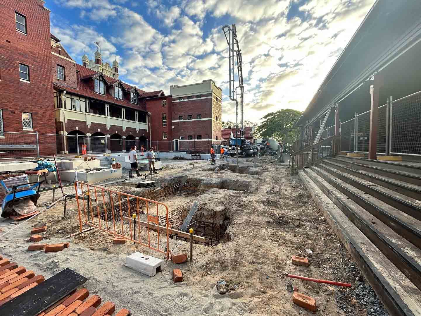 A Construction Site With a Brick Building in the Background — JIC Projects Pty Ltd in Runaway Bay, QLD