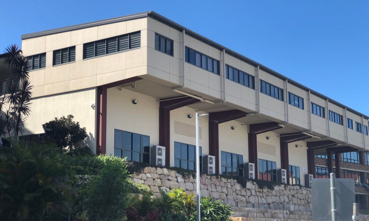 A Two-story Building With Large Windows, Surrounded by Greenery — JIC Projects Pty Ltd in Runaway Bay, QLD