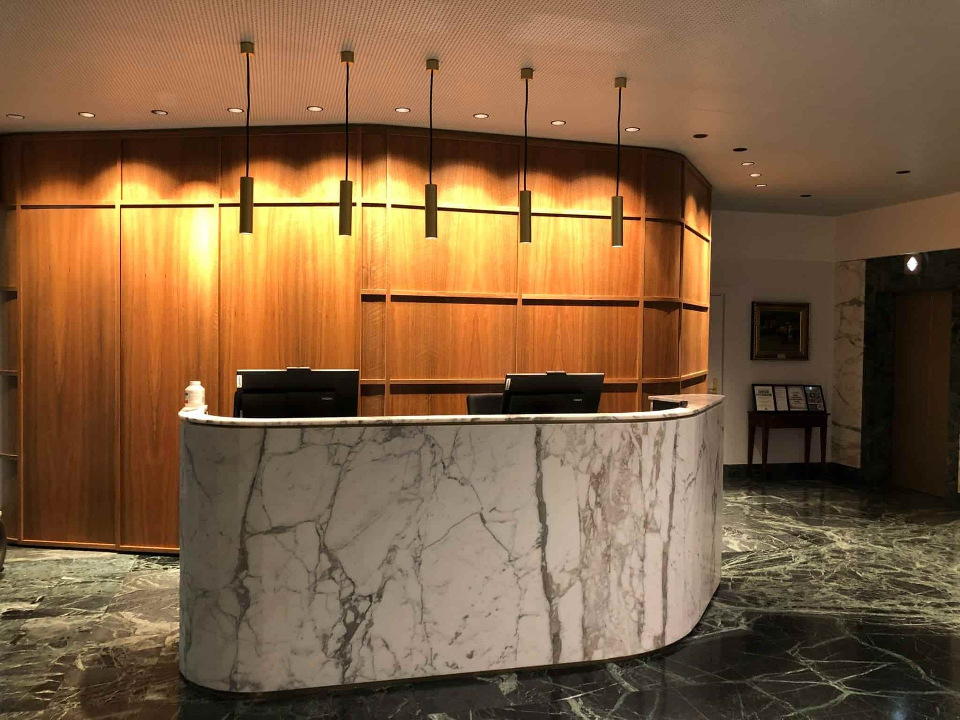 A curved marble reception desk  illuminated by ceiling lights — JIC Projects Pty Ltd in Runaway Bay, QLD