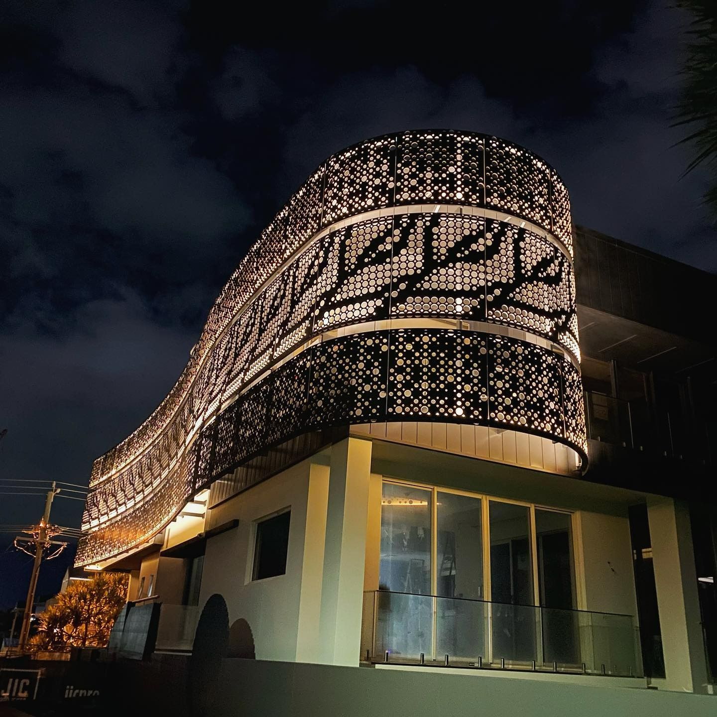 A Building Lit Up At Night With A Circular Design On The Side — JIC Projects Pty Ltd in Byron Bay, NSW