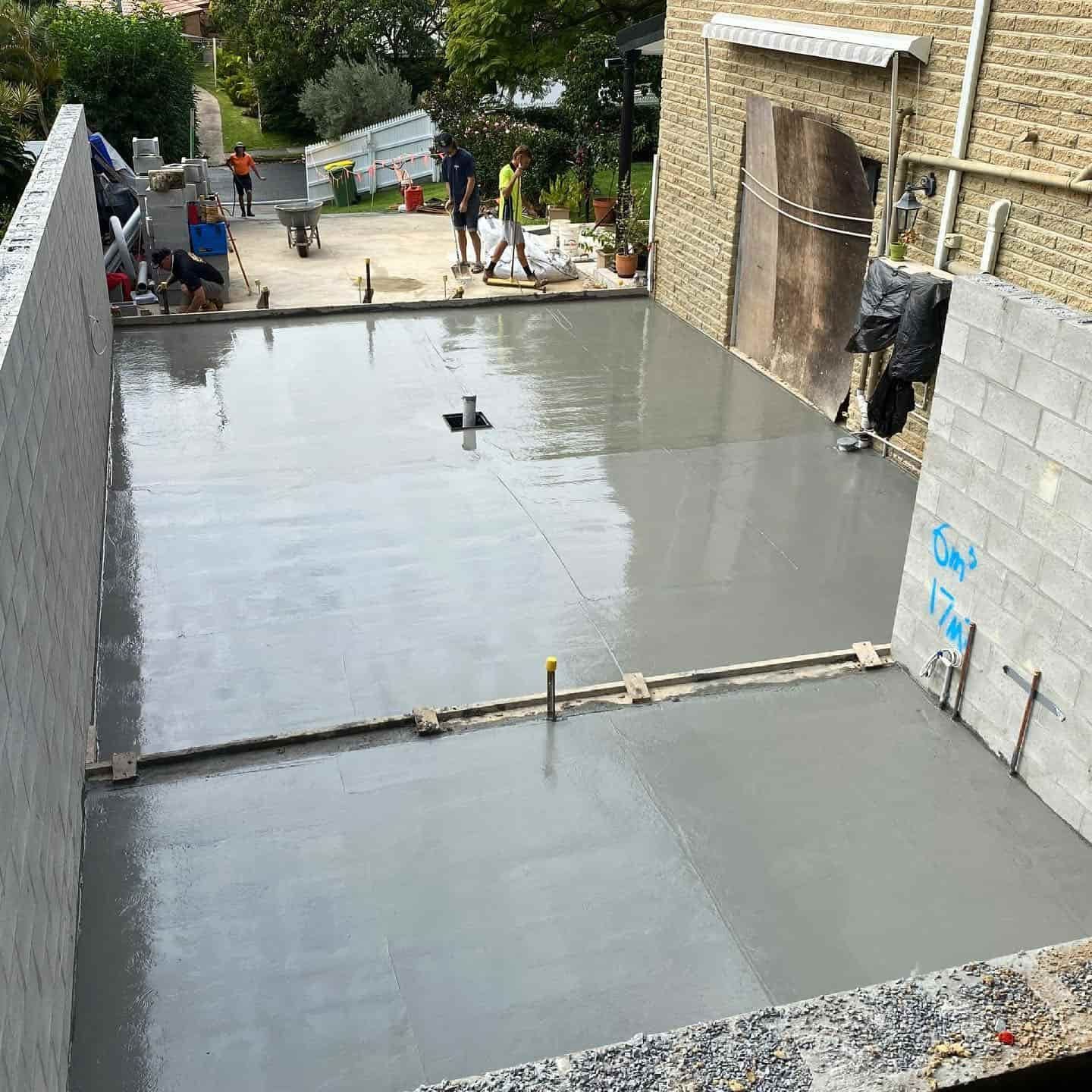 A Concrete Floor is Being Poured in Front of a Brick Building — JIC Projects Pty Ltd in Runaway Bay, QLD
