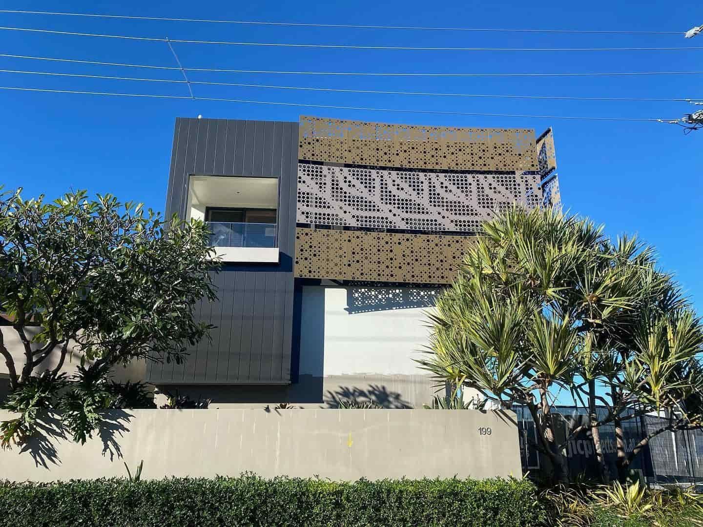 A Modern House With a Fence and Trees in Front of It — JIC Projects Pty Ltd in Runaway Bay, QLD