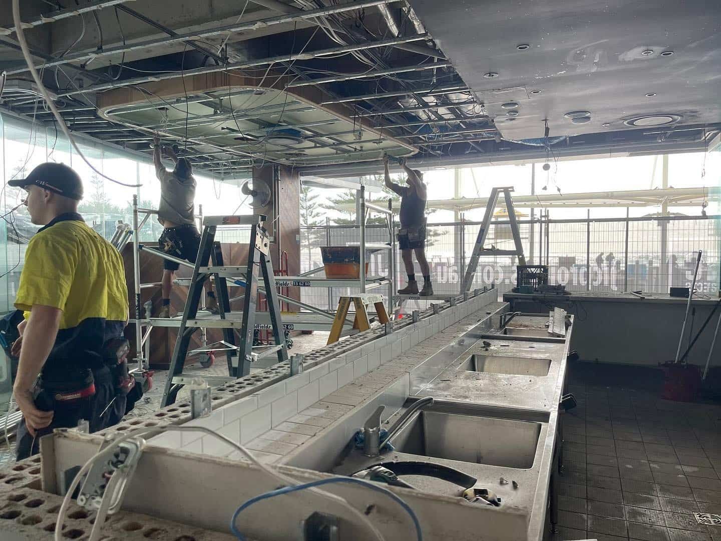 A Group of Men Are Working on the Ceiling of a Building — JIC Projects Pty Ltd in Tweed Heads, NSW