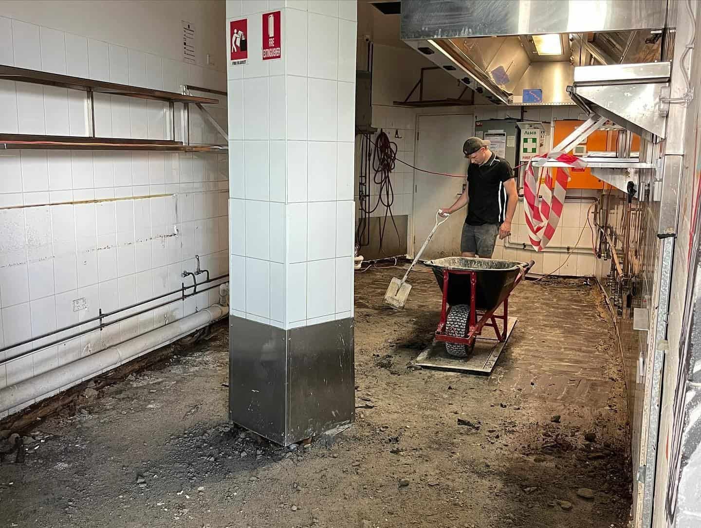 A Man is Working in a Kitchen With a Wheelbarrow — JIC Projects Pty Ltd in Runaway Bay, QLD