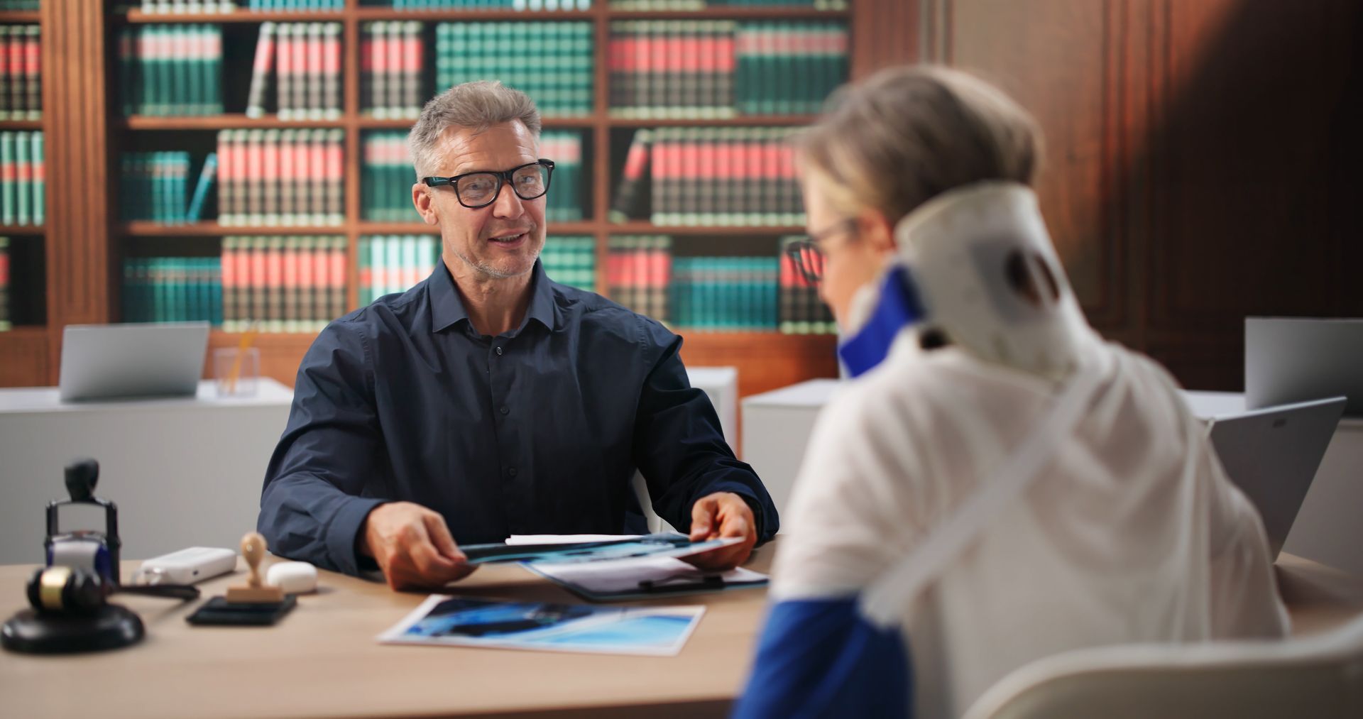 Injury Attorney meeting with a client wearing a neck brace in a law office.