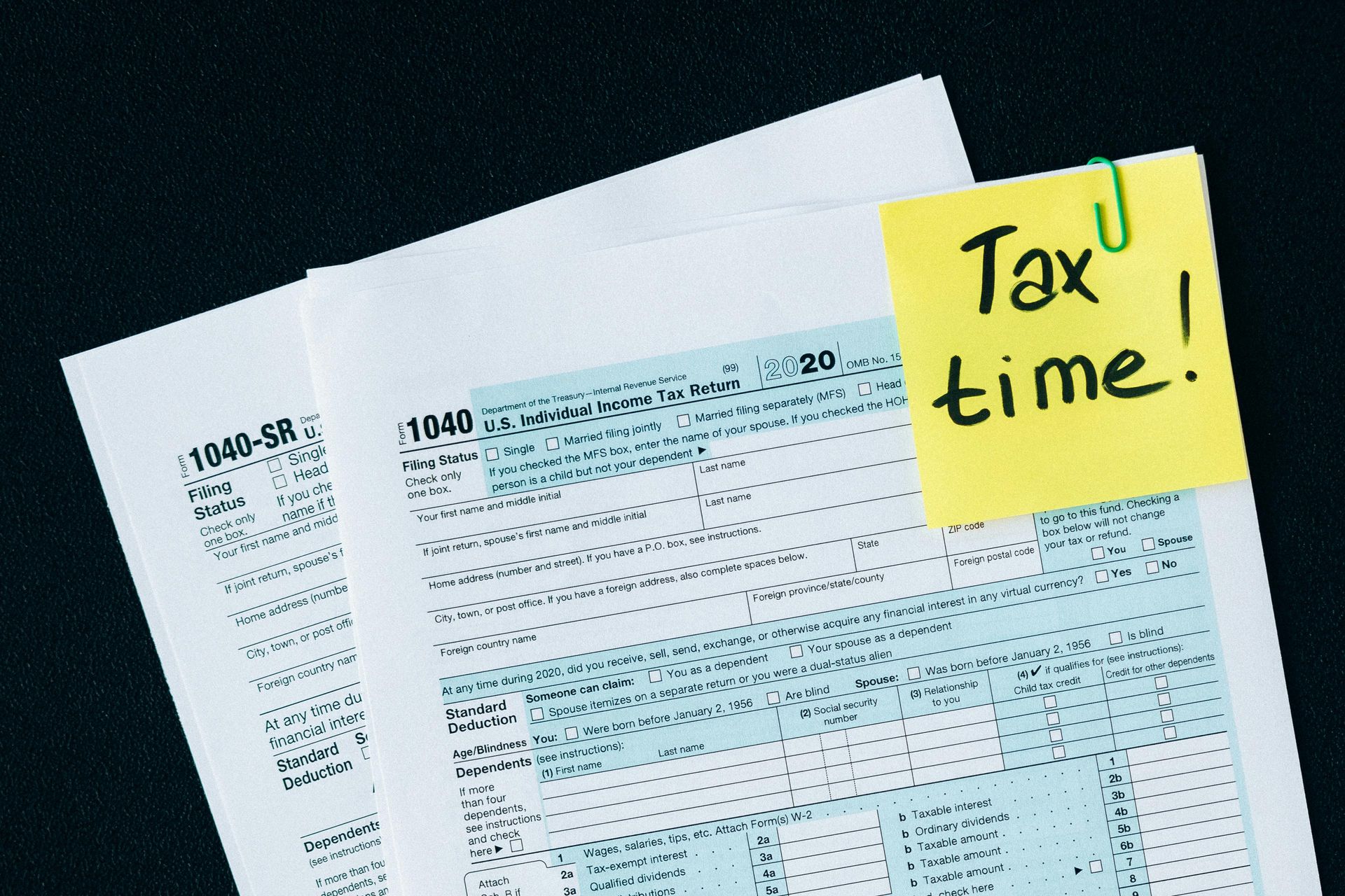 A calculator is sitting on top of a pile of papers next to a sticky note that says need help.
