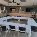 U-shaped banquet table with white tablecloths, blue water bottles, and black chairs in a modern room