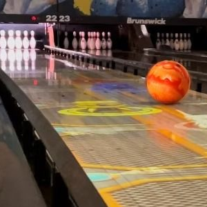 Bowling alley lane with an orange ball rolling toward pins and a 250 score graphic on the lane