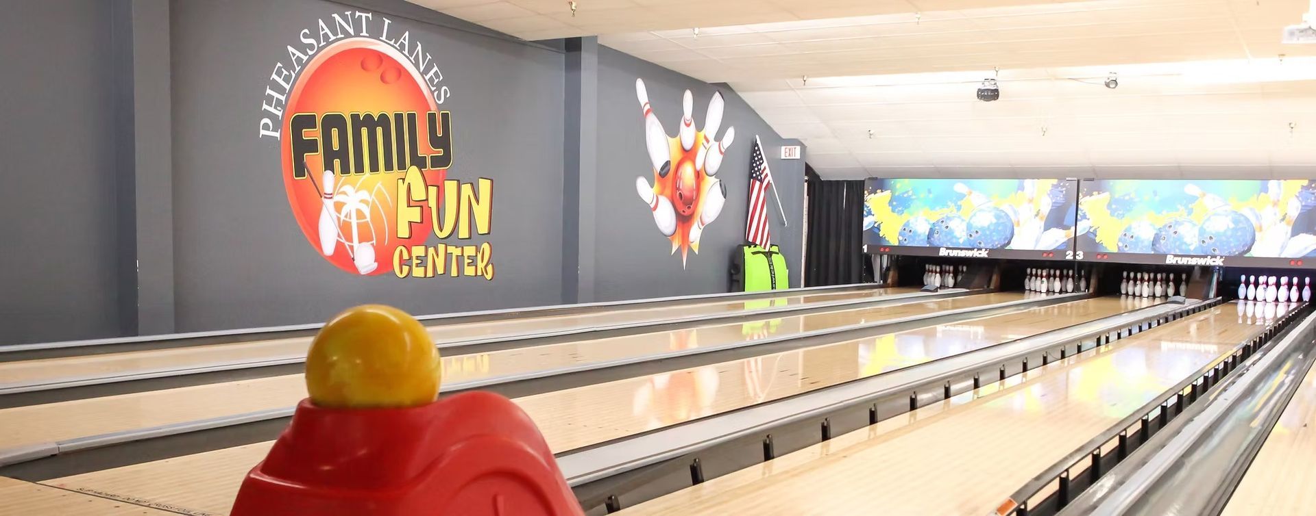 Empty bowling alley with colorful “Family Fun” mural and a red ball return in the foreground