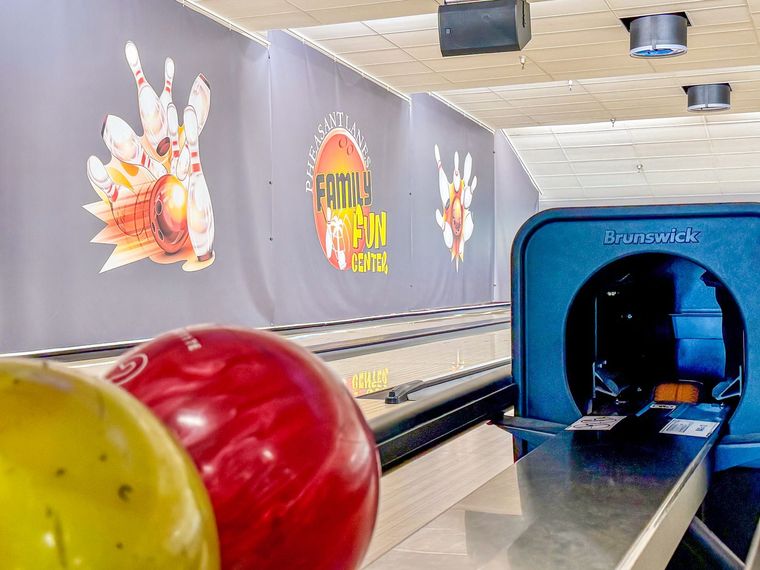 White bowling pin on a lane with a Family Fun Center sign in the background