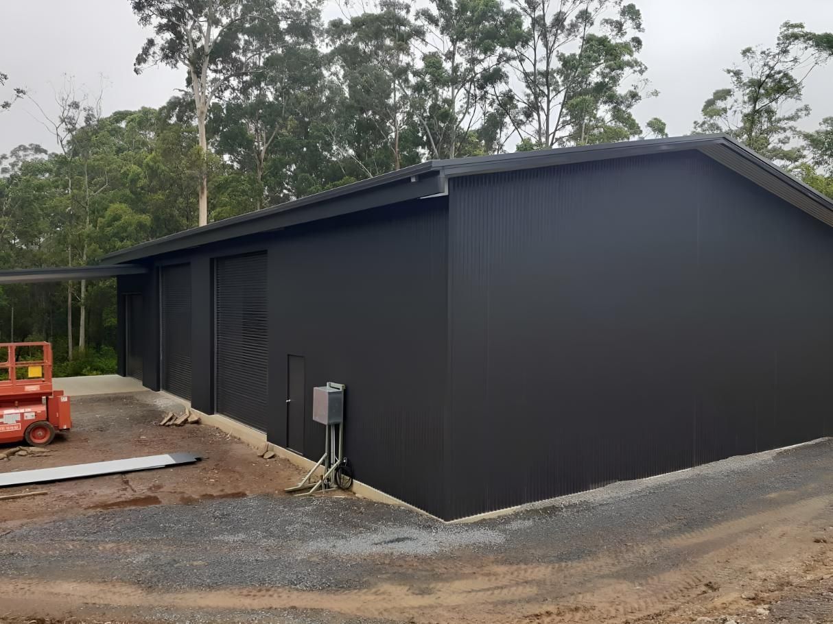 A Large Black Building is Being Built in the Middle of a Dirt Field — Hastings Valley Sheds in Port Macquarie, NSW