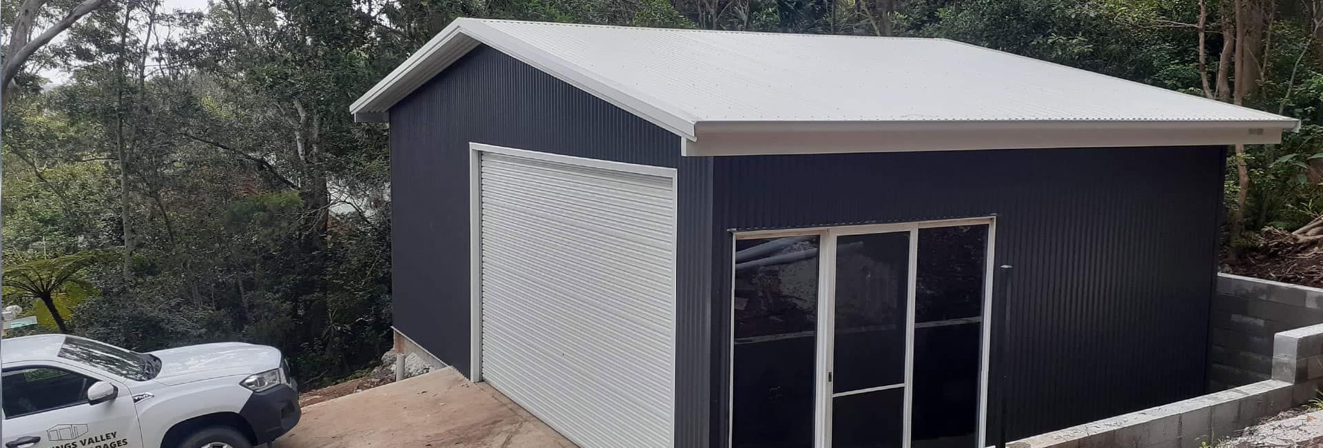 A Black and White Garage With a White Truck Parked in Front of It — Hastings Valley Sheds in Wauchope, NSW