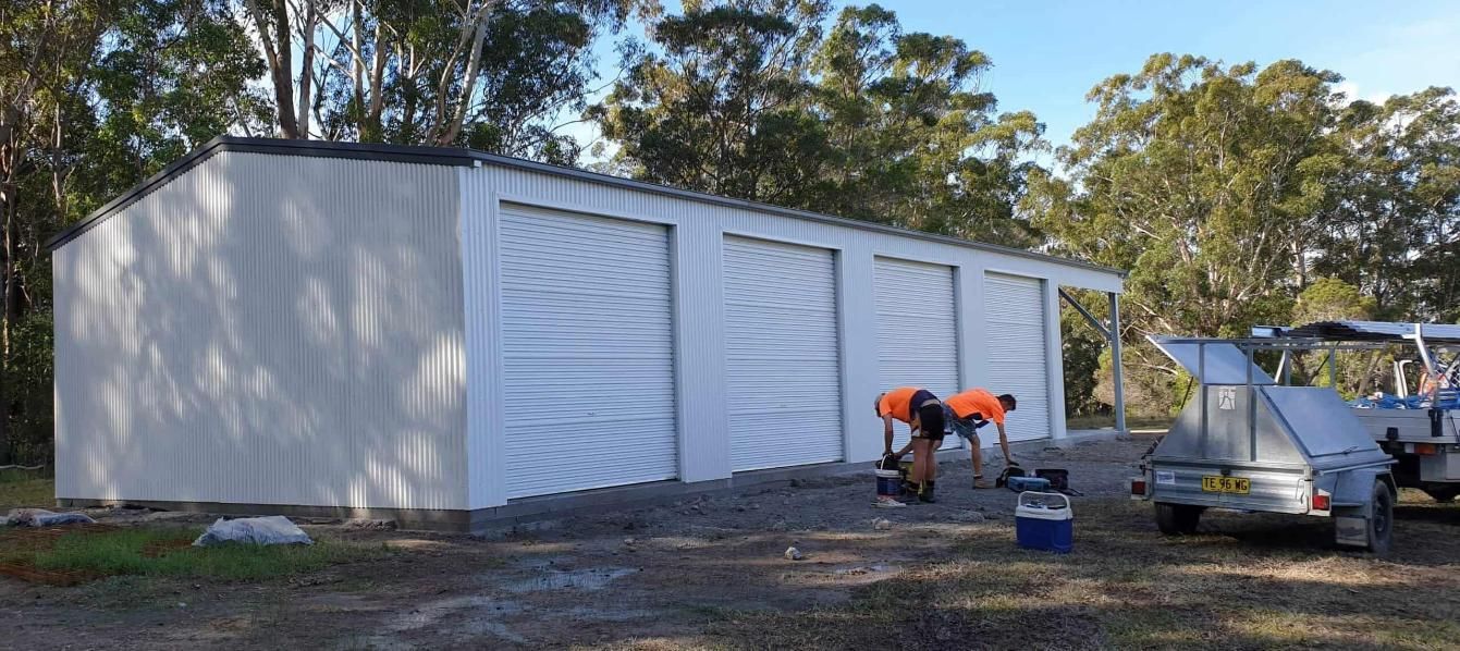 A Group of Men Are Working on a Large White Building — Hastings Valley Sheds in South West Rocks, NSW